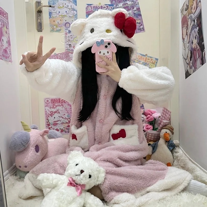 Pessoa com roupão rosa e branco da Hello Kitty com capuz de orelhinhas e laço vermelho, sentada em um quarto