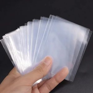 Maço de sleeves transparentes de 65 x 90 mm segurado na mão