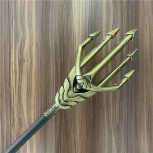 Cabeça dourada do tridente de cosplay estilo Aquaman com haste preta em fundo de madeira